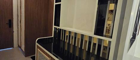 A hallway with a wooden door, a white wall, and a black and white patterned cabinet.