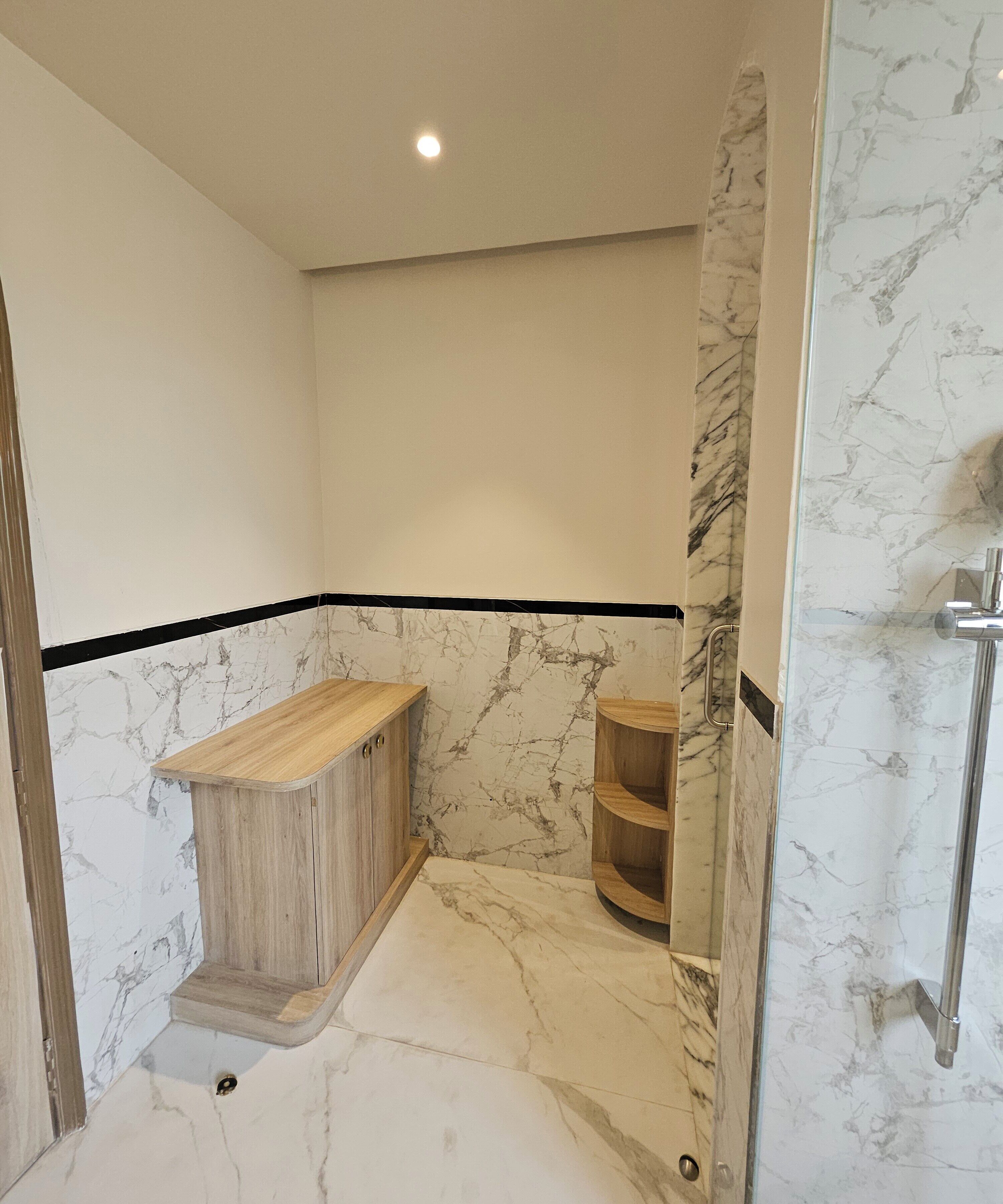 A bathroom with marble walls and a wooden vanity.