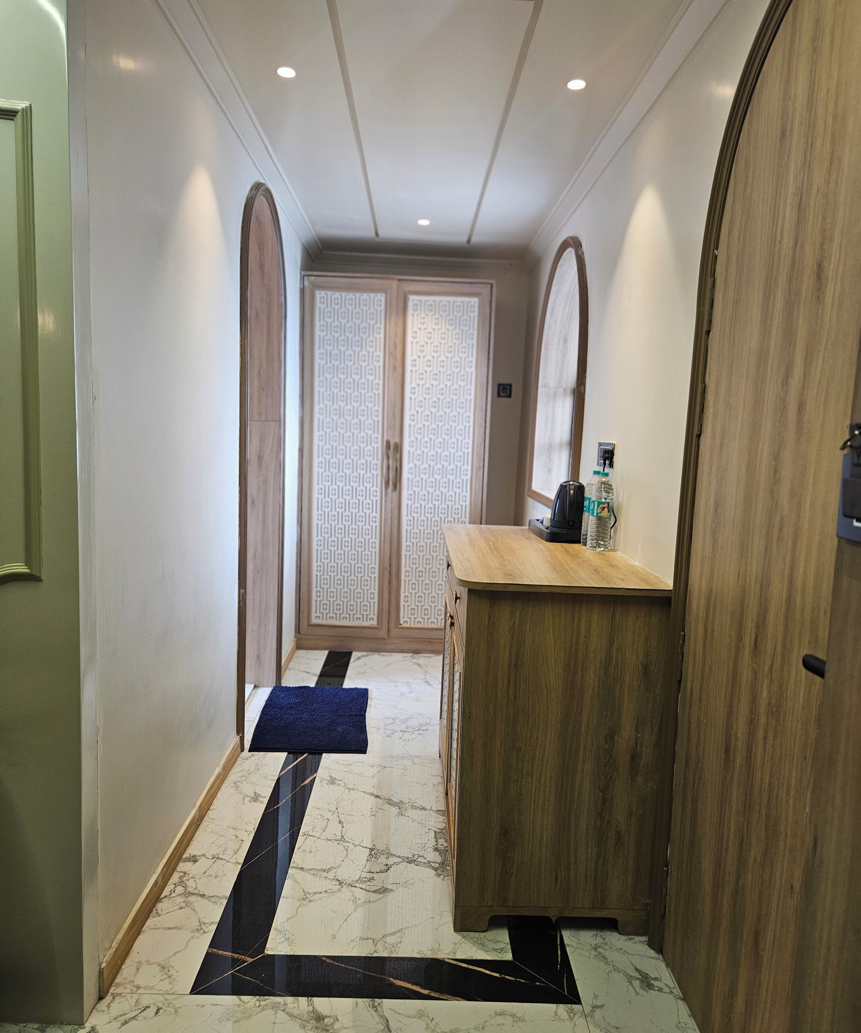 Un pasillo con un mostrador de madera, un tapete azul y una puerta con diseño.