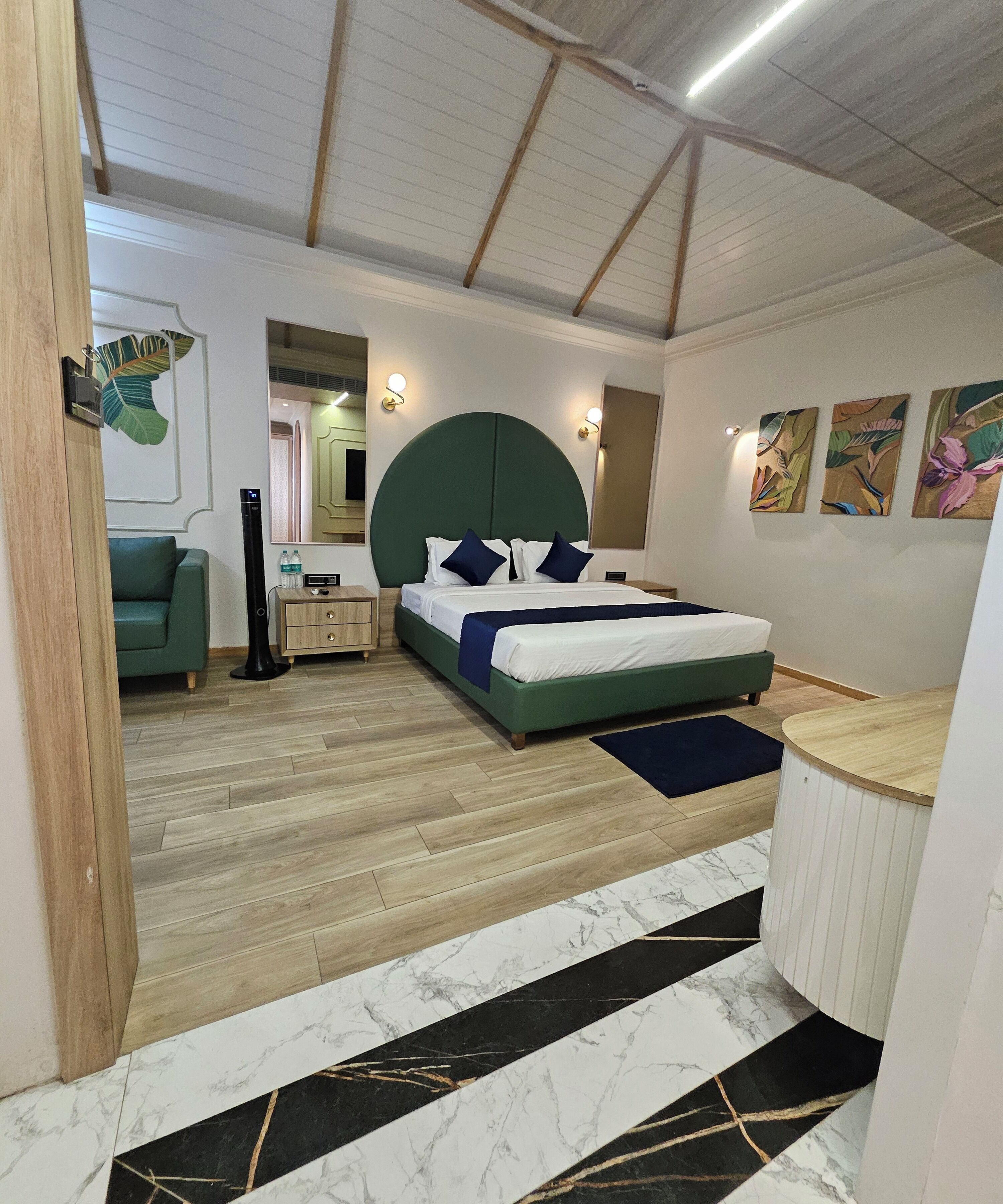 Un dormitorio moderno con una cama grande, un cabecero verde, piso de madera y una alfombra con diseño de mármol.