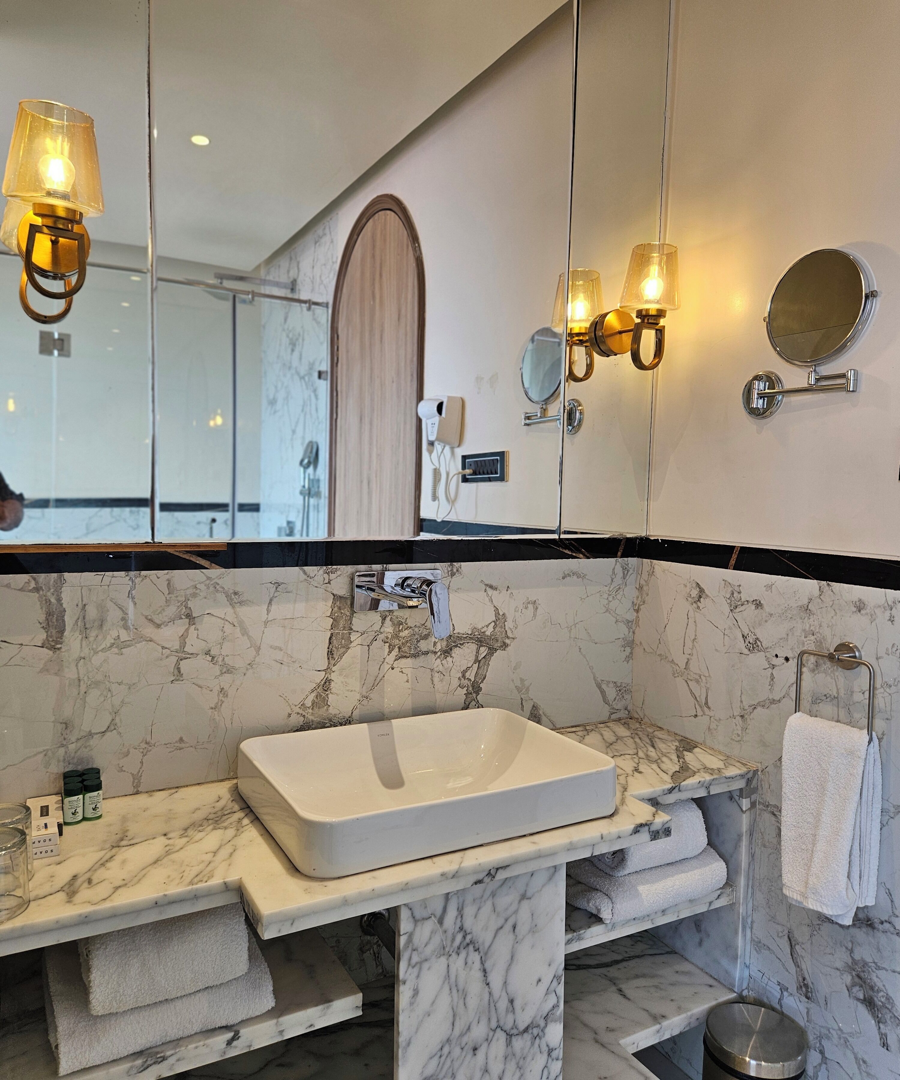 A bathroom with a marble sink, a mirror, and two wall-mounted lights.