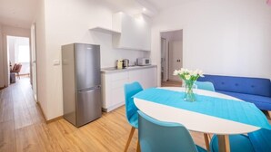 A modern kitchen with white cabinets, a stainless steel refrigerator, and a blue dining table with four chairs. - One step away from Juliet's House, Piazza Erbe and Ponte Pietra quiet area (Verona)
