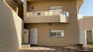 Un immeuble moderne à deux étages, doté d’une façade en briques, d’un balcon à l’étage supérieur et d’une entrée sécurisée par un portail.