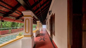 Ein Korridor mit rotem Bodenbelag, weißen Säulen mit gelben Akzenten und einer Decke in Rot mit aufwendigen Verzierungen.