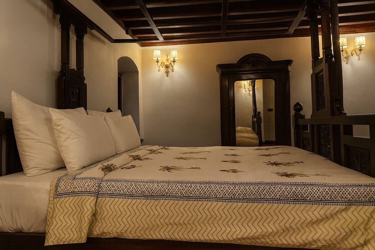 Ein Schlafzimmer mit einem großen Bett, einem Holzkopfteil, einem Spiegel und Wandleuchten.