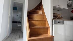 A wooden staircase leading to a second floor, white walls, and a kitchen area with a Bosch dishwasher. - Welcome to the Terns! The dune house. (Barneville-Carteret)