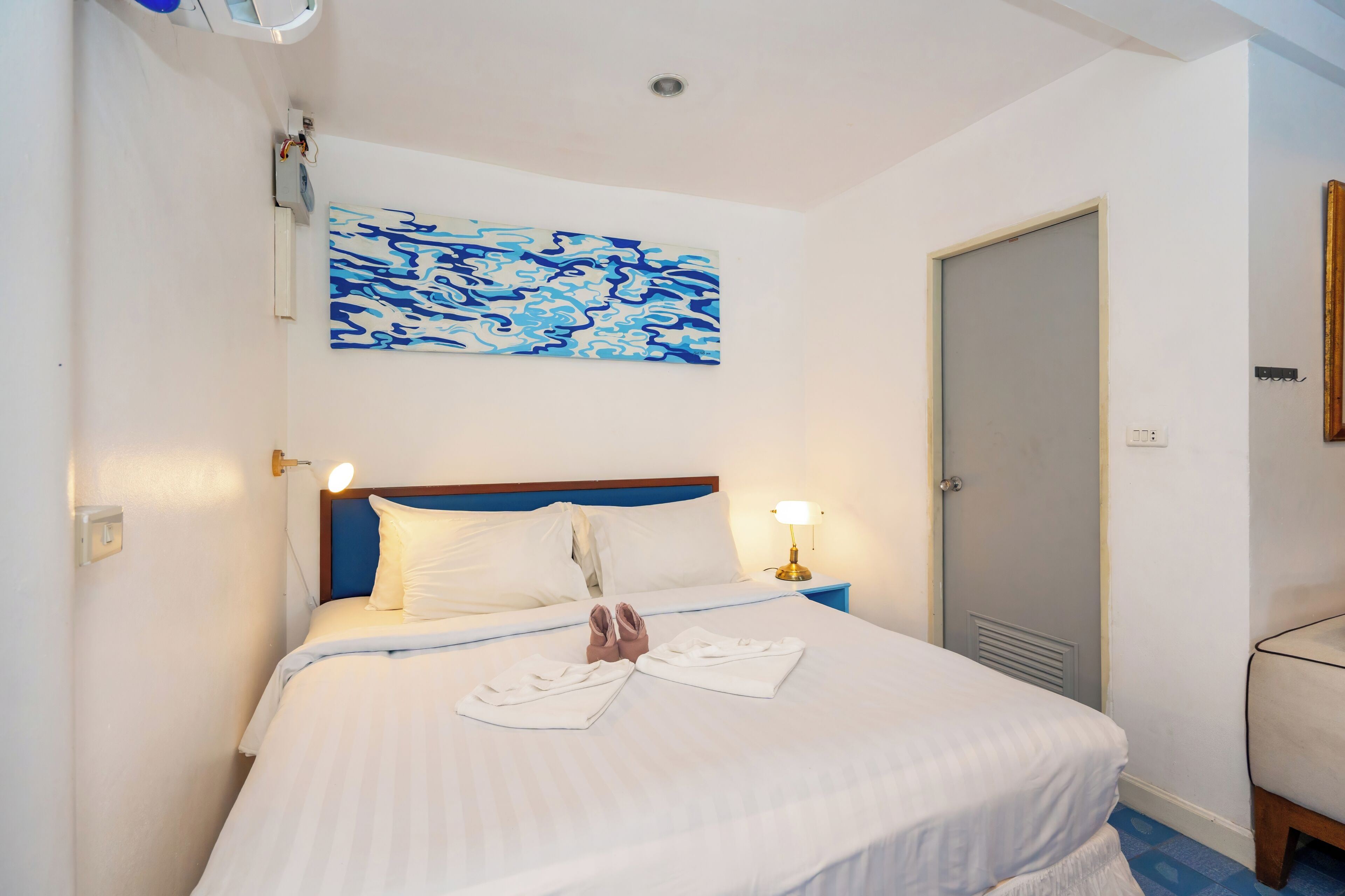 Ein Hotelzimmer mit einem Bett, einem Nachttisch, einer Wandleuchte und einer Tür.