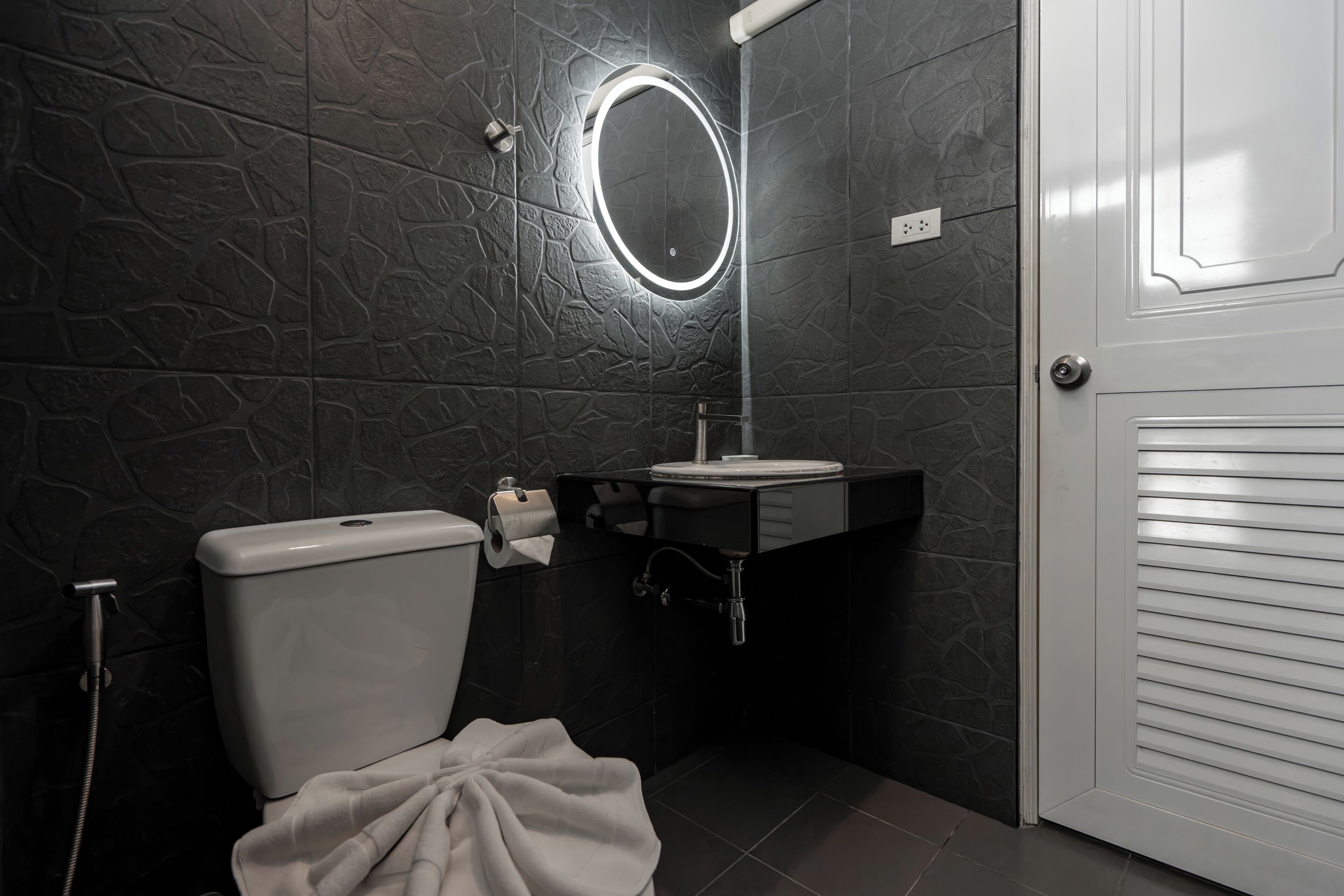 A bathroom with a toilet, sink, and mirror.