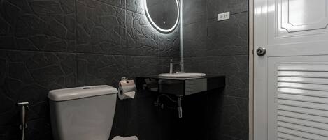 A bathroom with a toilet, sink, and mirror.