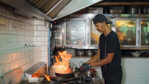 Una cocina con un fogón y una sartén en llamas.