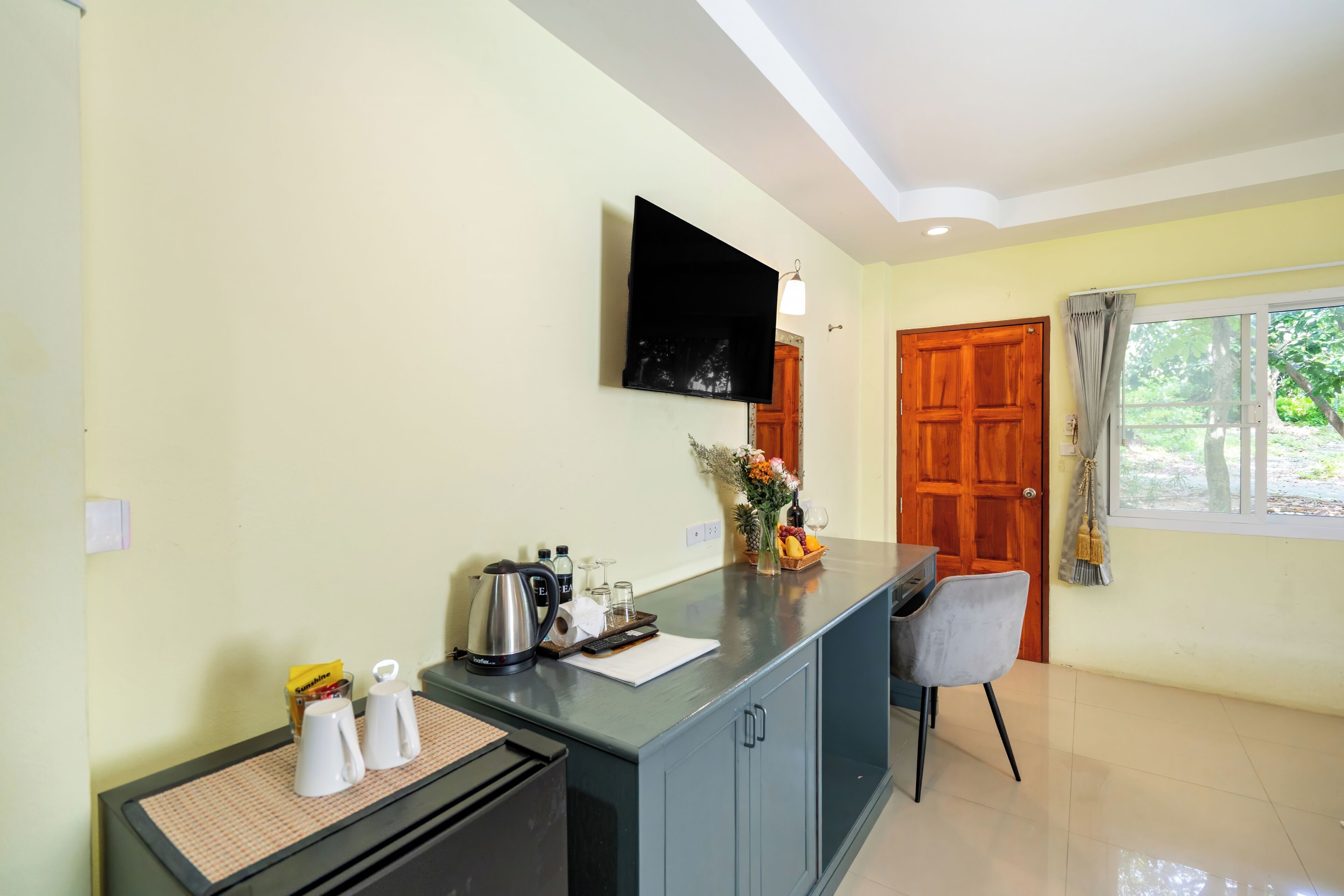 A clean, well-lit kitchen area with a coffee maker, tea kettle, and a fruit basket on the counter.