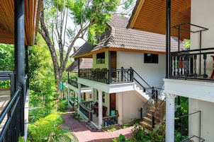 A two-story building with a balcony, a staircase, and a garden area.
