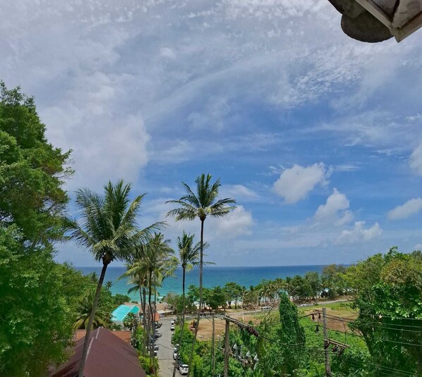 A coastal view with palm trees, a clear sky, and a road leading to a beach area. - Oceanview Bungalows by EAT, Karon Beach (Karon)