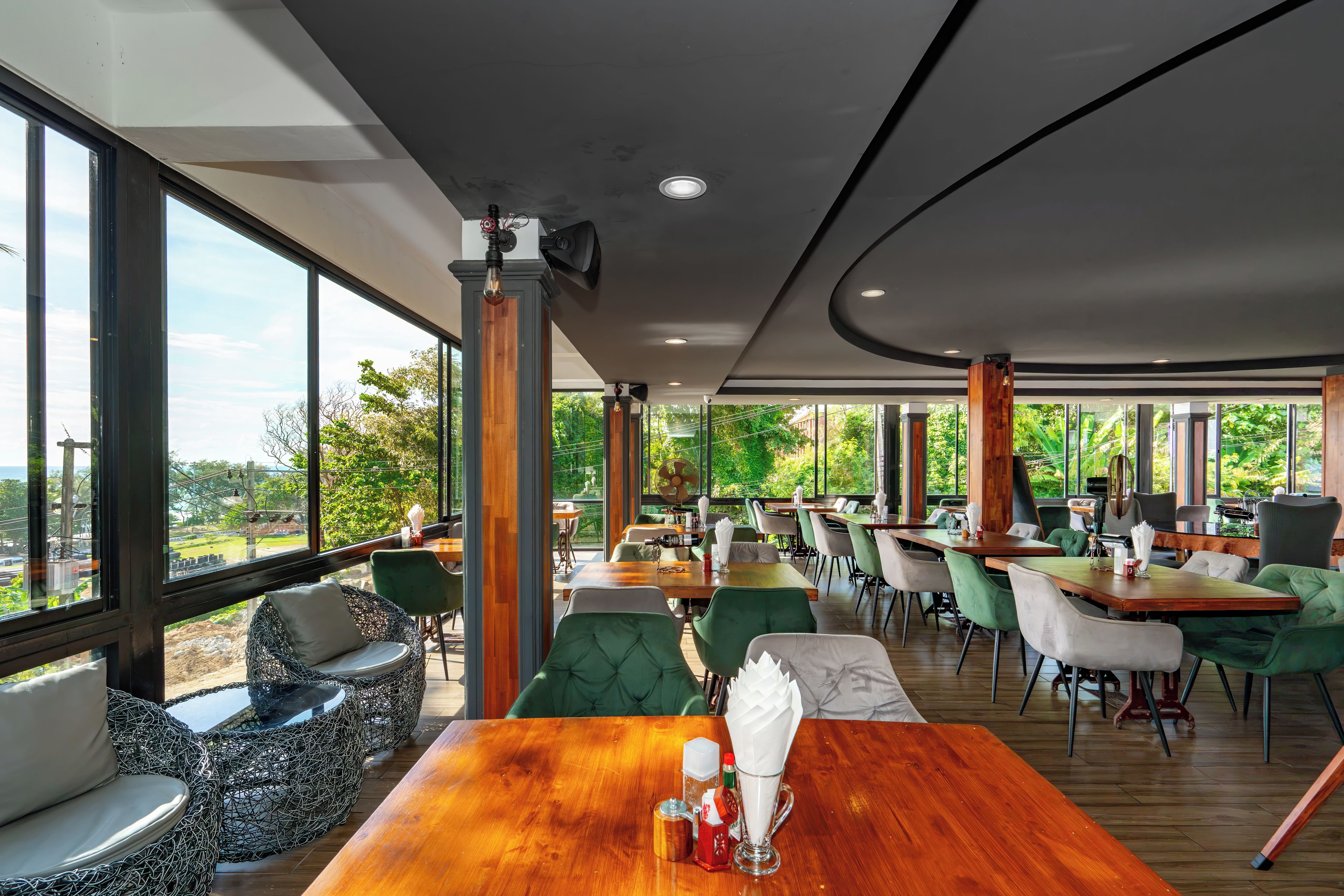 Un restaurante espacioso con techos altos, ventanas amplias y diversas opciones de asientos, incluyendo mesas y sillas.