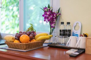 A table with a fruit basket, water bottles, and a remote control. - Oceanview Bungalows by EAT, Karon Beach (Karon)