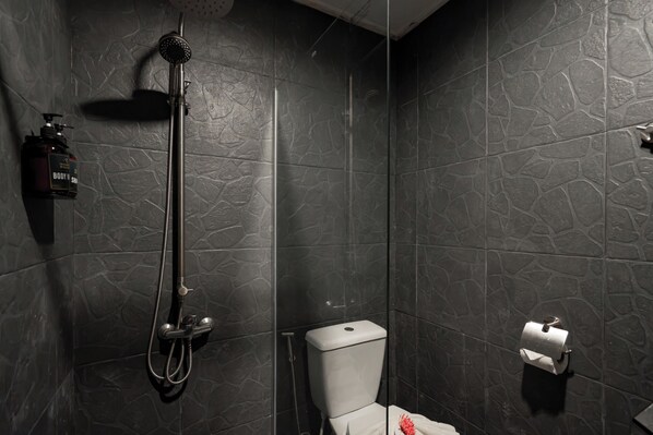 Un baño con ducha, inodoro y una botella de jabón corporal.