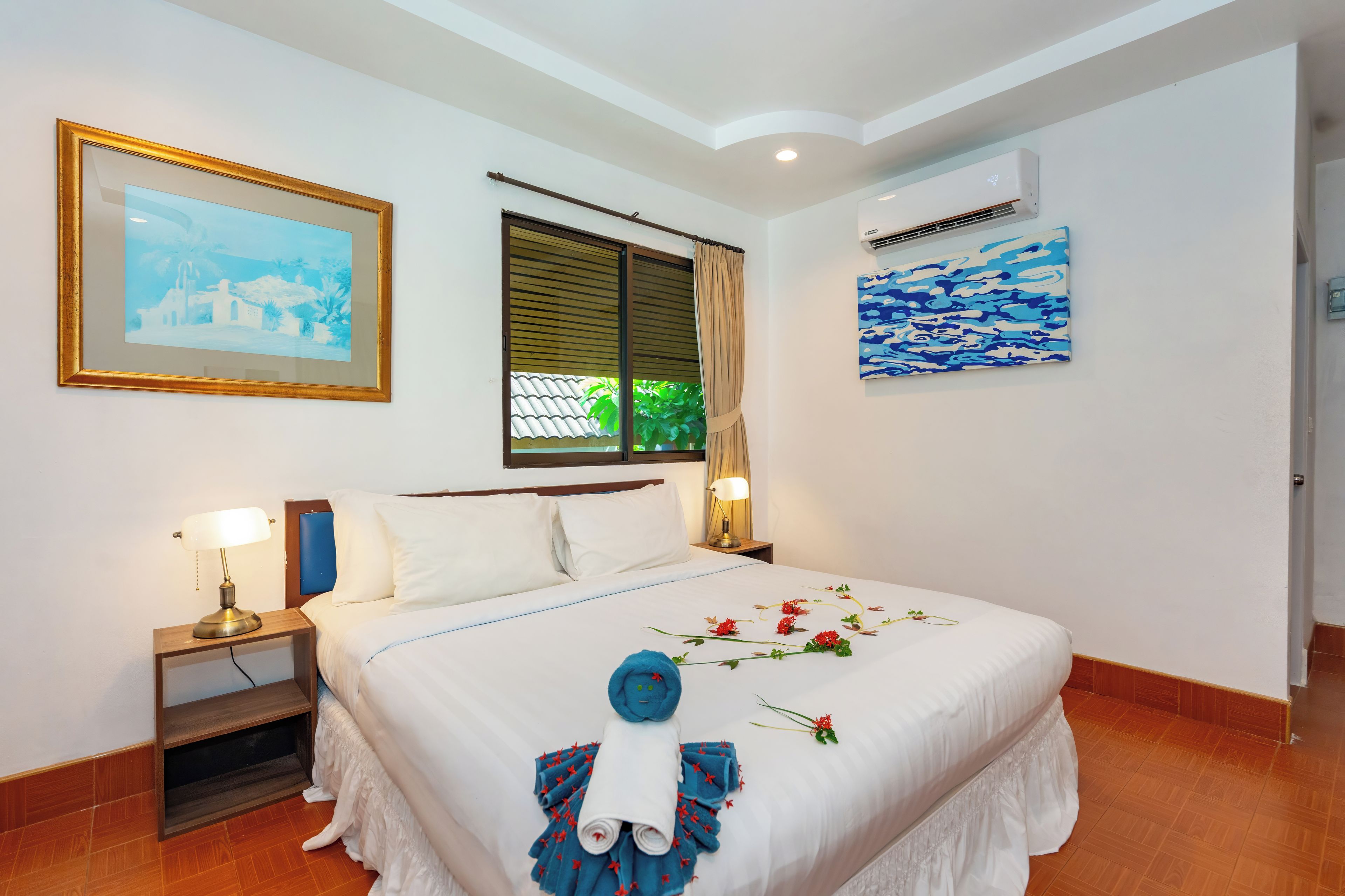 Une chambre d’hôtel avec un lit, une table de chevet, un climatiseur fixé au mur et un tableau encadré.