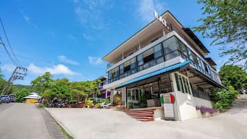 Un edificio moderno de dos pisos con un área de estar al aire libre techada y un letrero para un restaurante.