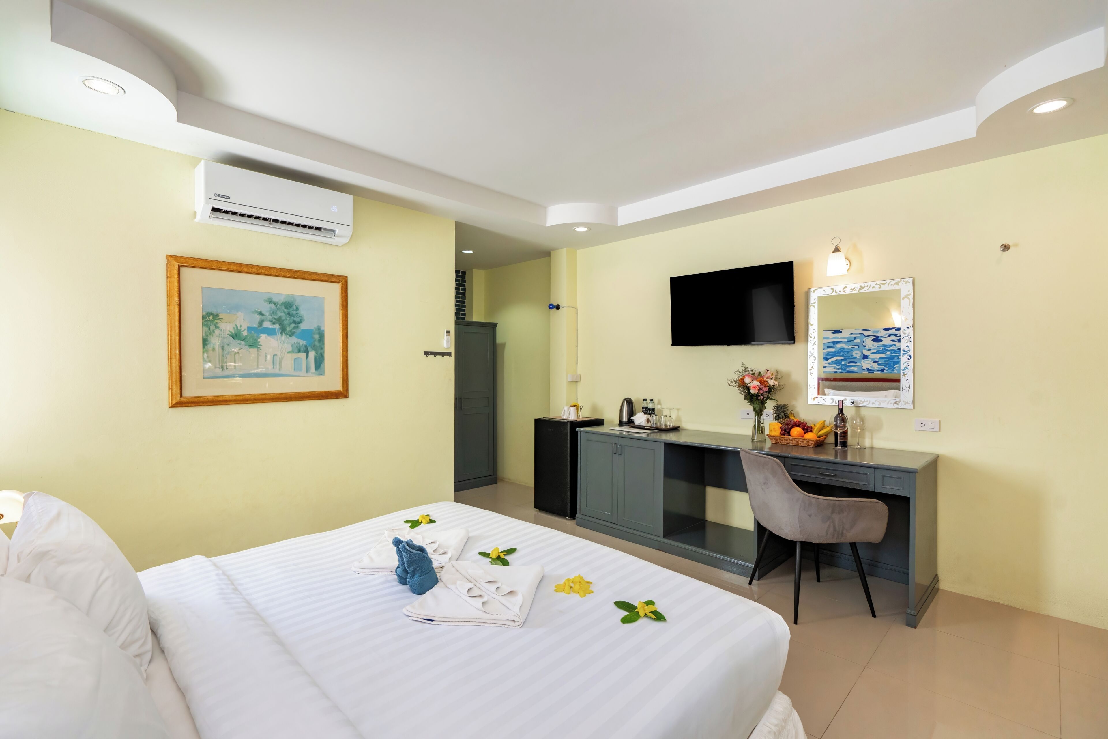 Una habitación de hotel con una cama, un escritorio, un televisor y un espejo.