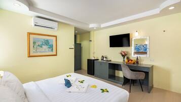 Una habitación de hotel con una cama, un escritorio, un televisor y un espejo.