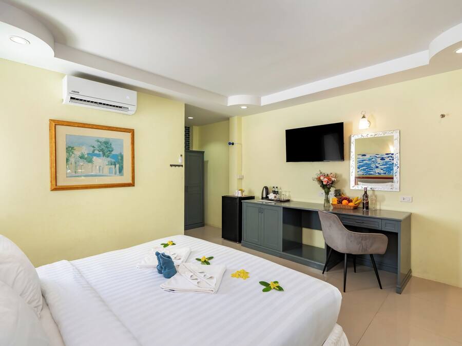 Una habitación de hotel con una cama, un escritorio, un televisor y un espejo.