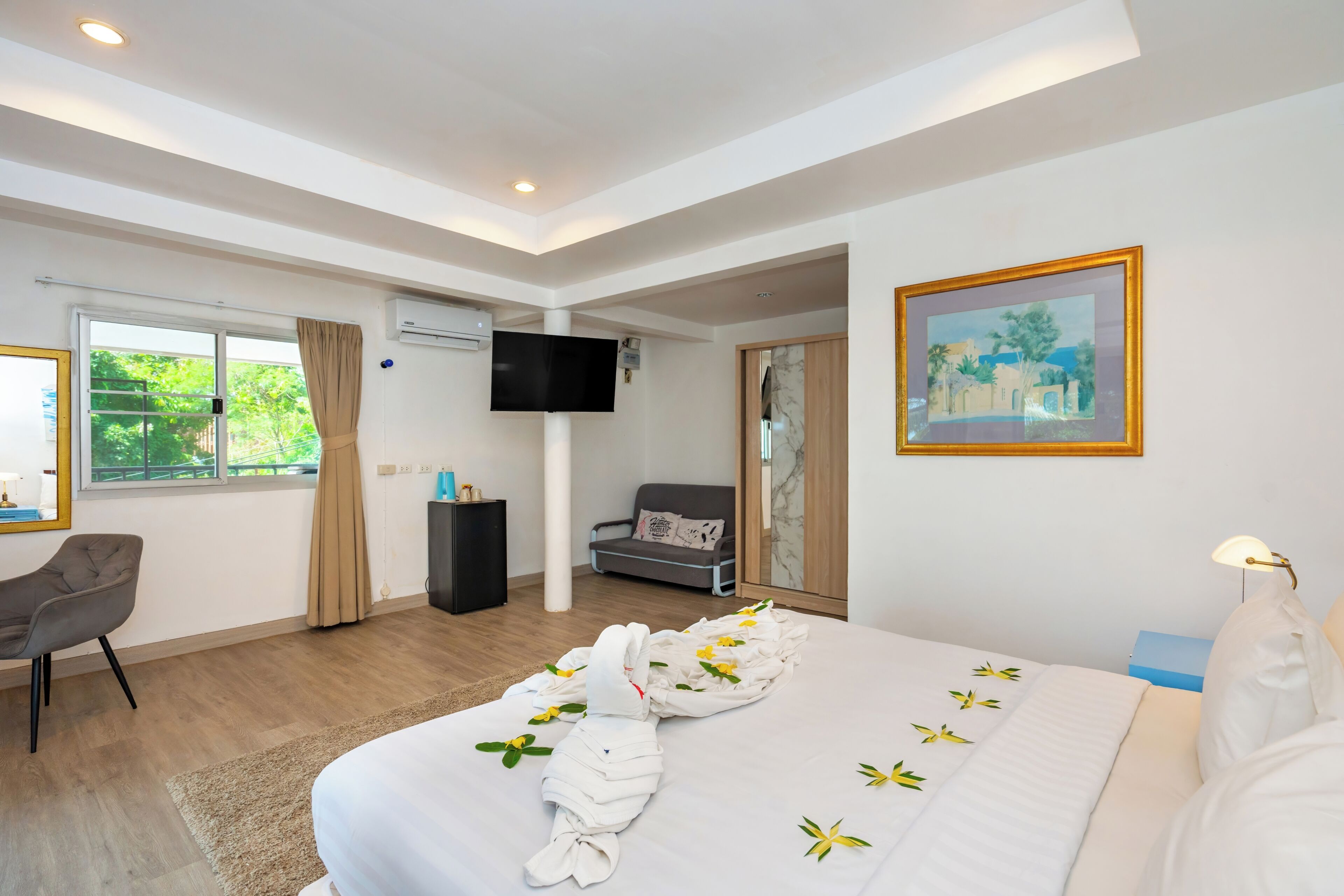 A hotel room with a bed, a desk, a chair, a television, and a painting on the wall.