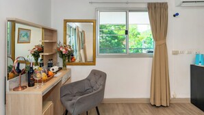 A room with a wooden desk, a chair, a large mirror, a window with curtains, and an air conditioning unit. - Oceanview Bungalows by EAT, Karon Beach (Karon)