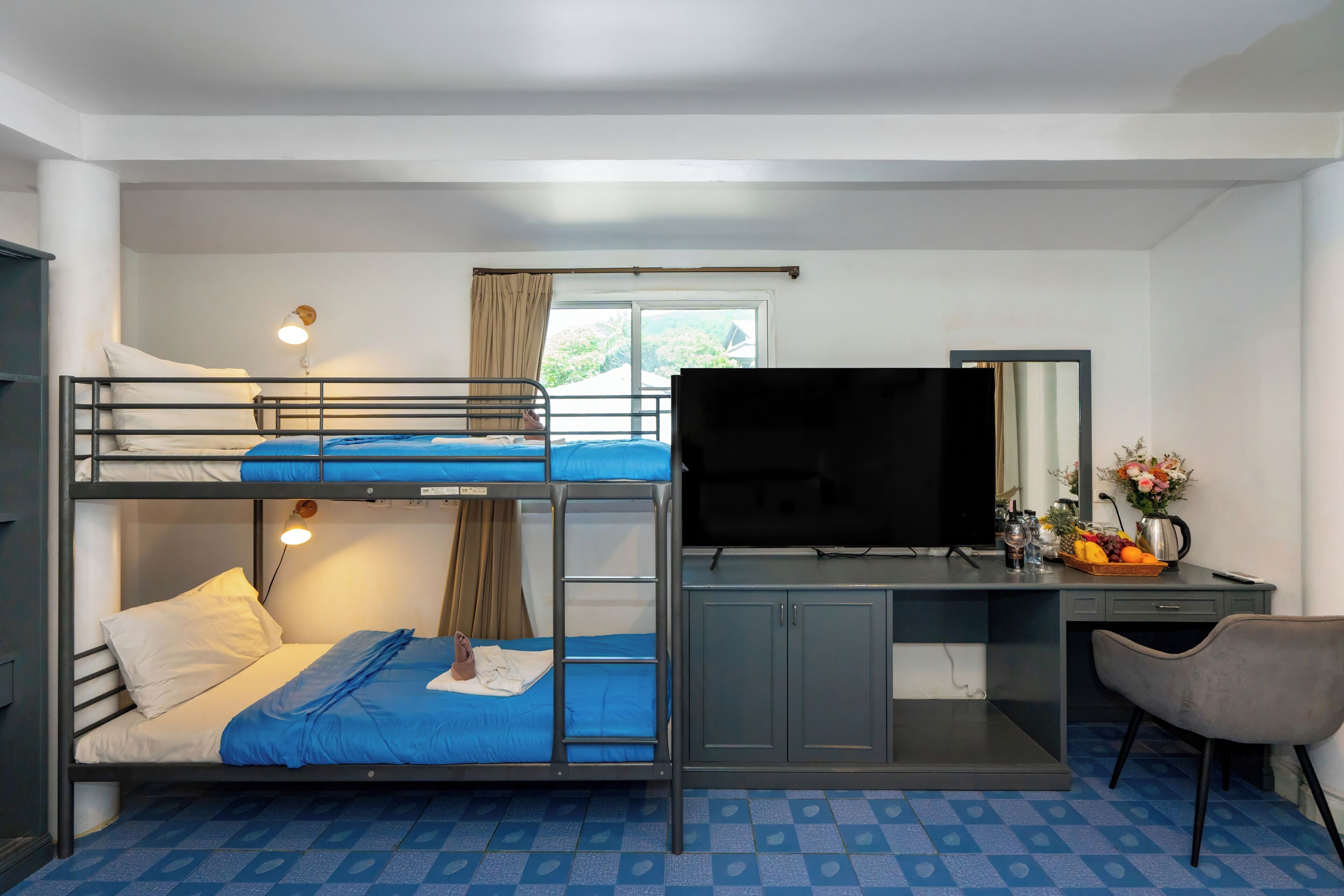 A bunk bed room with a desk, TV, and a chair.