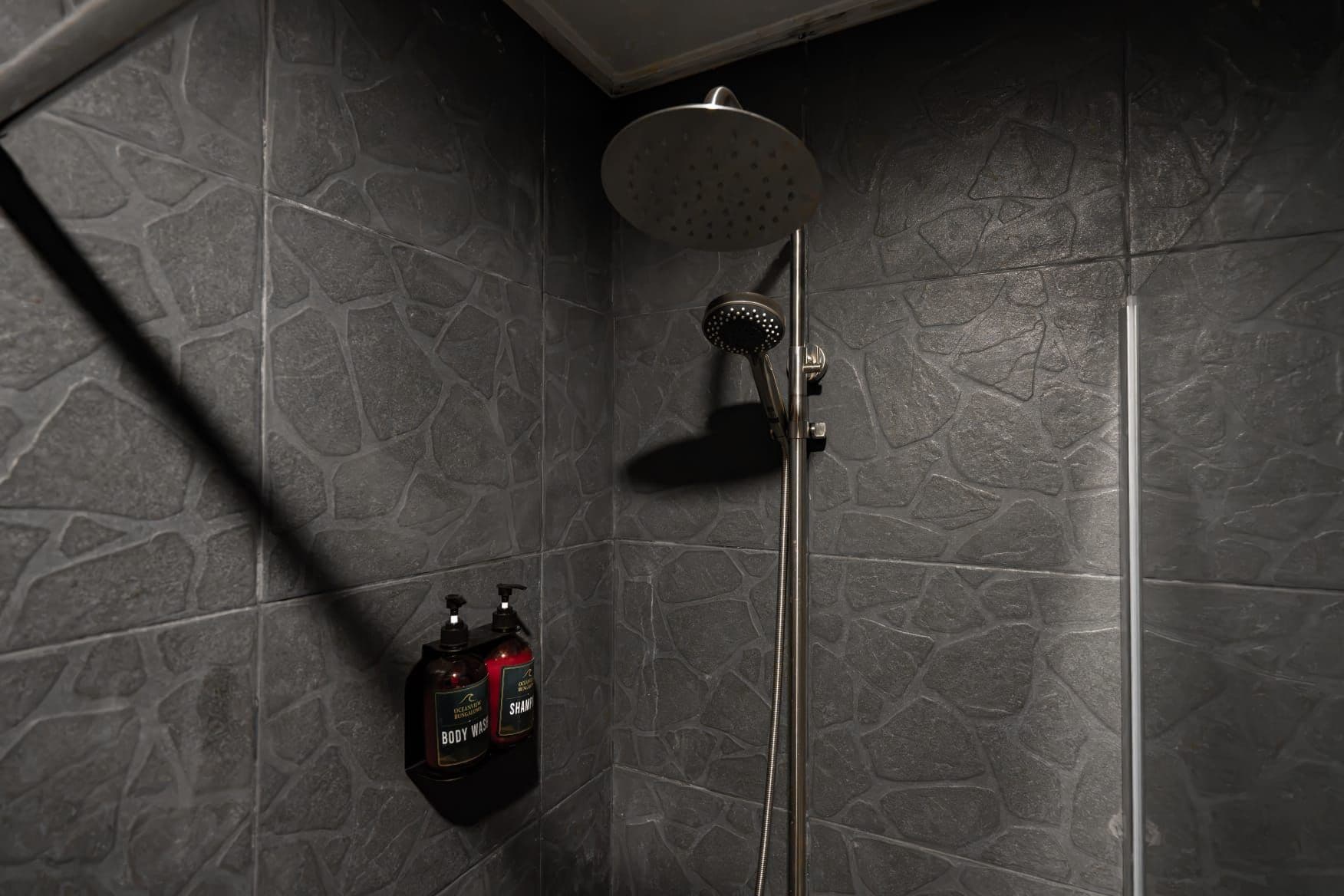Une douche équipée d’un pommeau de douche à main et d’un distributeur de savon fixé au mur.