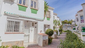 Un edificio bianco con inferriate, un tendone verde e una base in pietra.