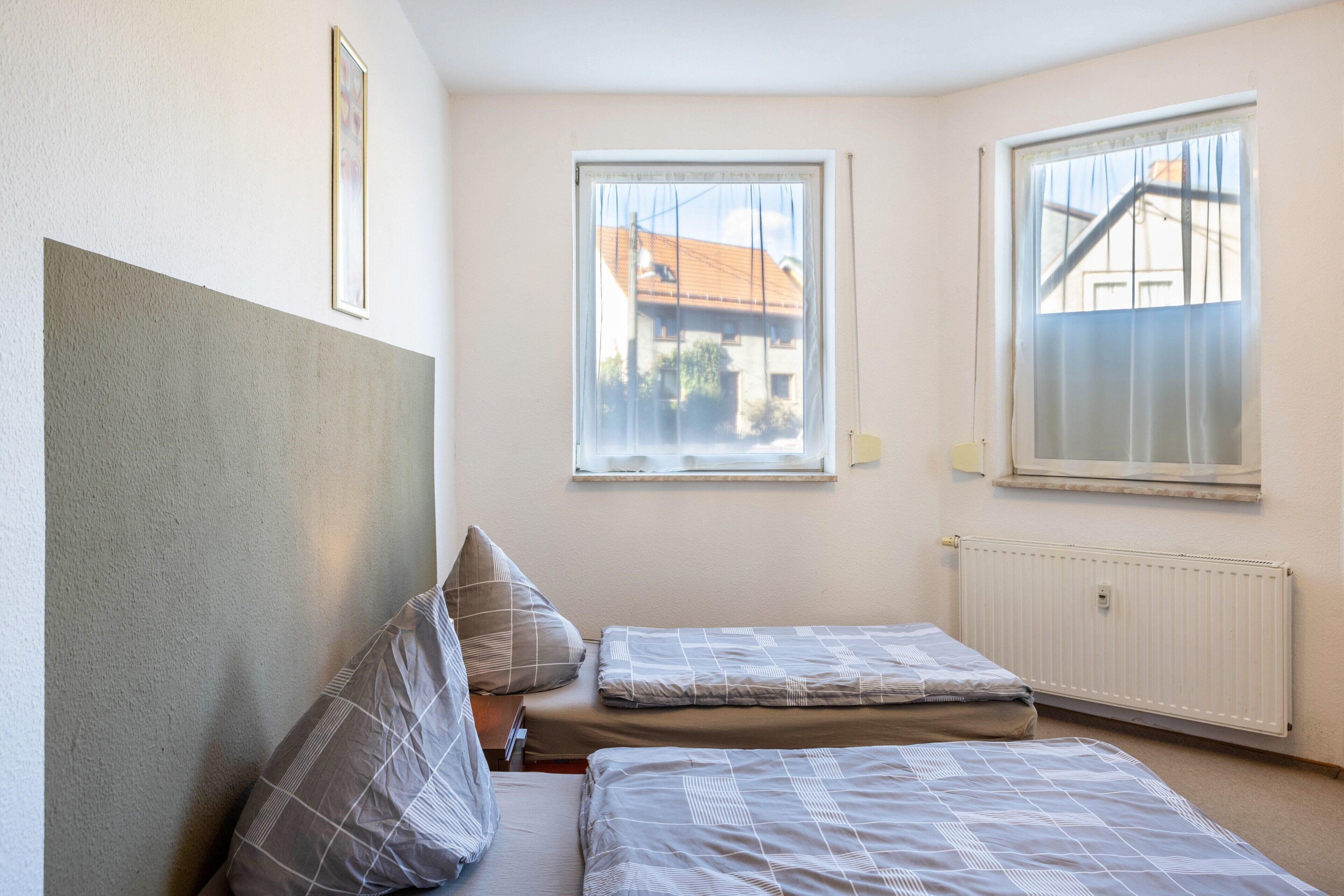 A bedroom with two beds, a window with a view, and a radiator.