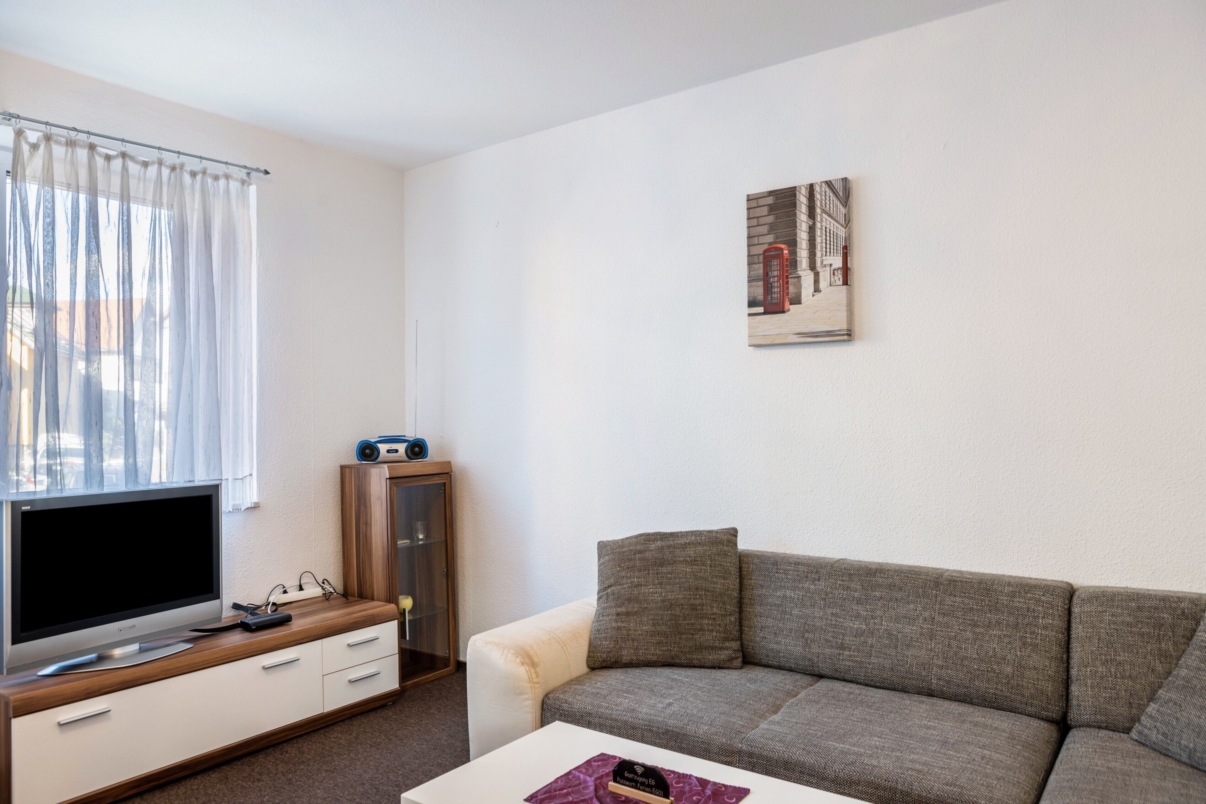 Una sala de estar con una televisión de pantalla plana, un sofá, una mesa de centro y un aparador.