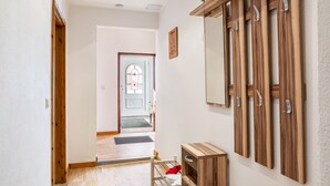 Um corredor com piso de madeira, um armário de madeira com espelho e uma porta que dá para outro quarto.