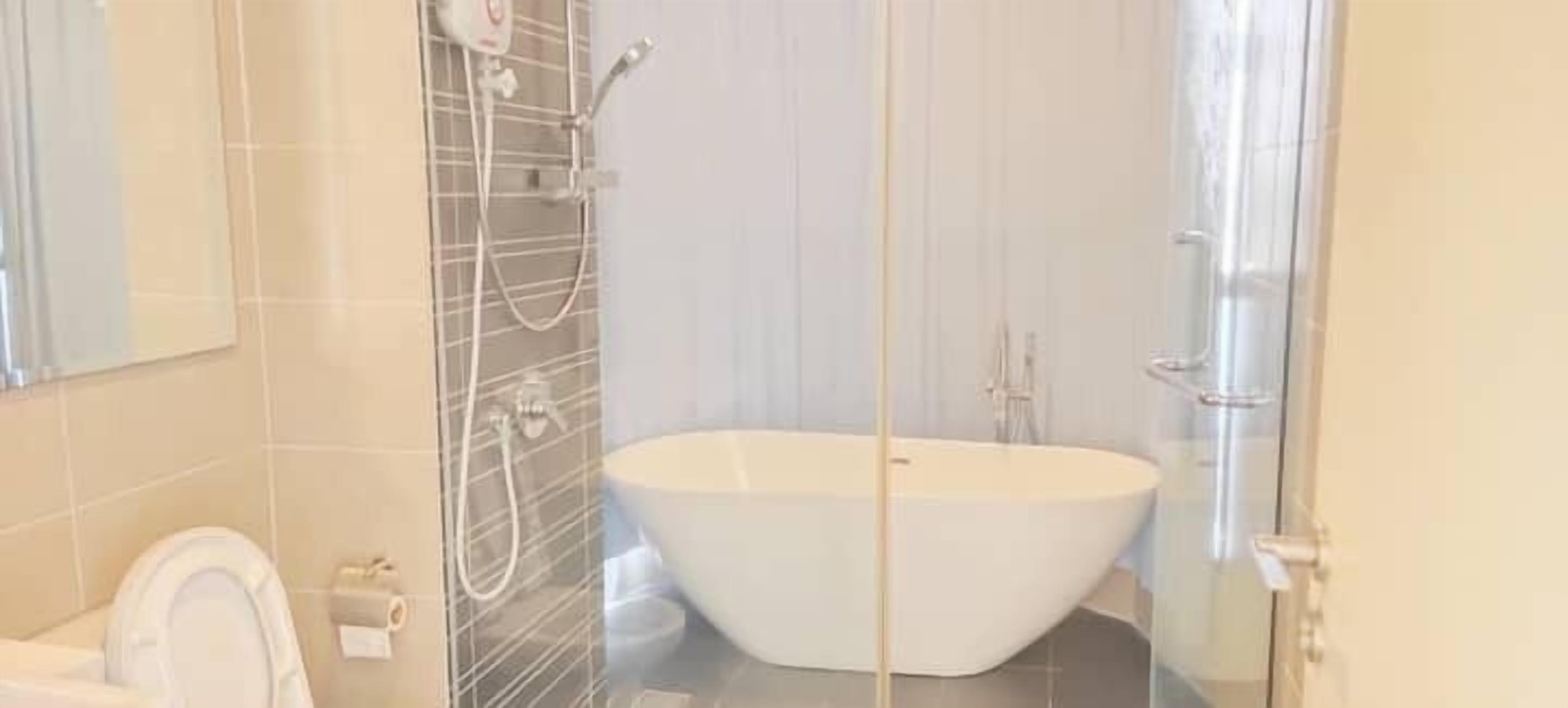 A modern bathroom with a freestanding bathtub, a glass shower enclosure, and a toilet.