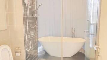 A modern bathroom with a freestanding bathtub, a glass shower enclosure, and a toilet.