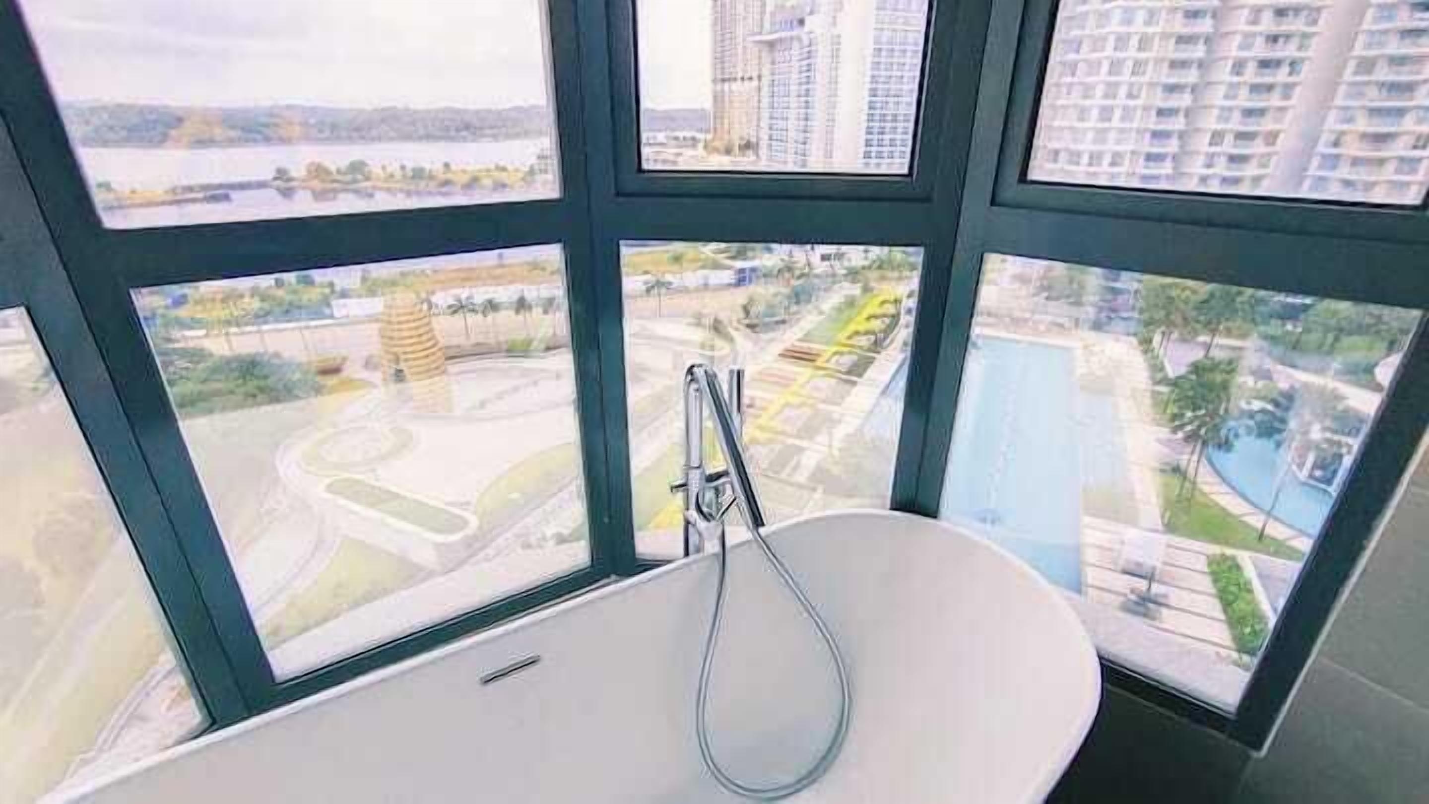A bathroom with a bathtub and multiple windows offering views of a cityscape.