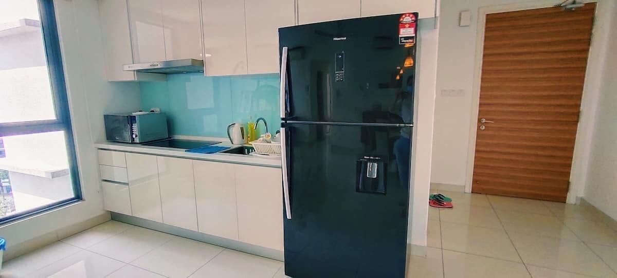 A kitchen with white cabinets, a black refrigerator, a microwave, and a sink.