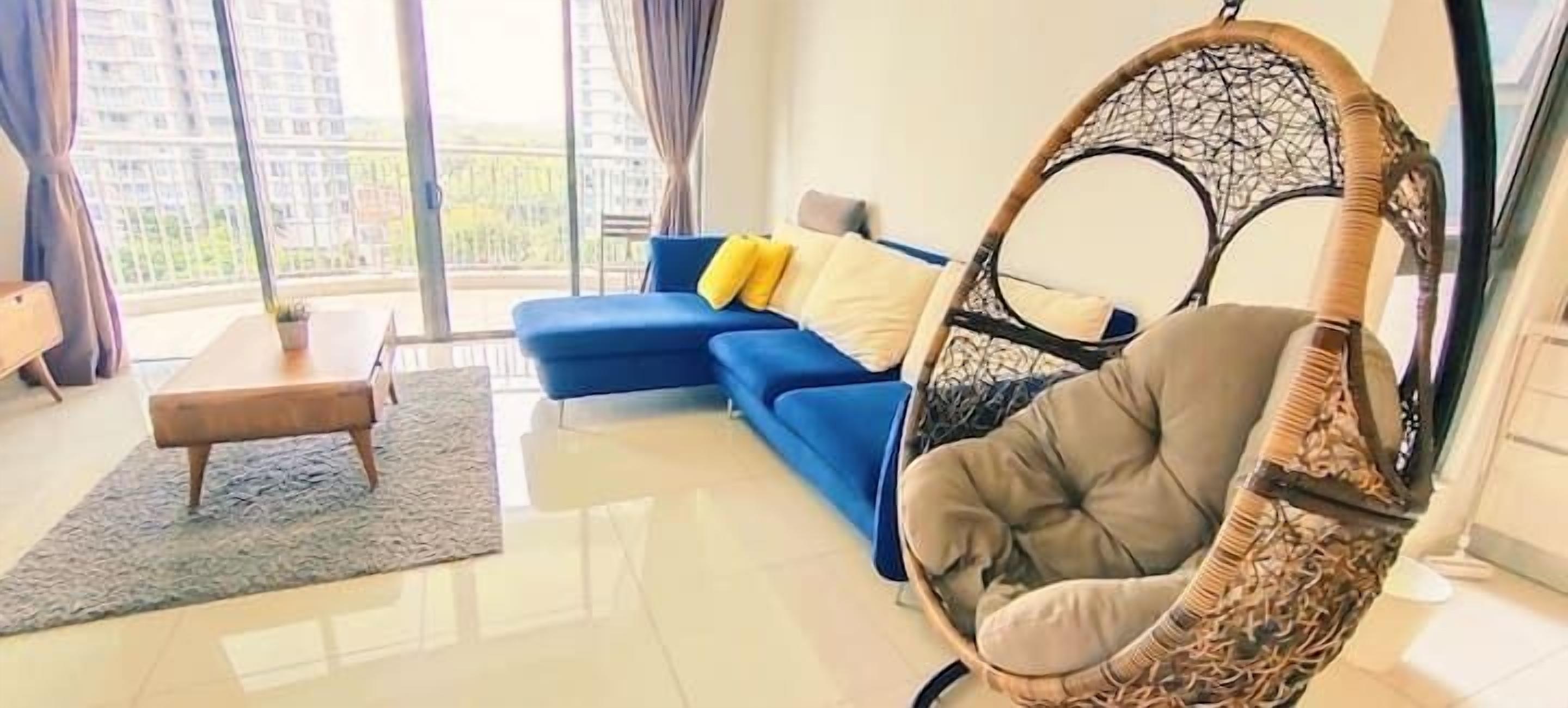 Ein Wohnzimmer mit einem blauen Sofa, einem Hängesessel und einem kleinen Tisch.