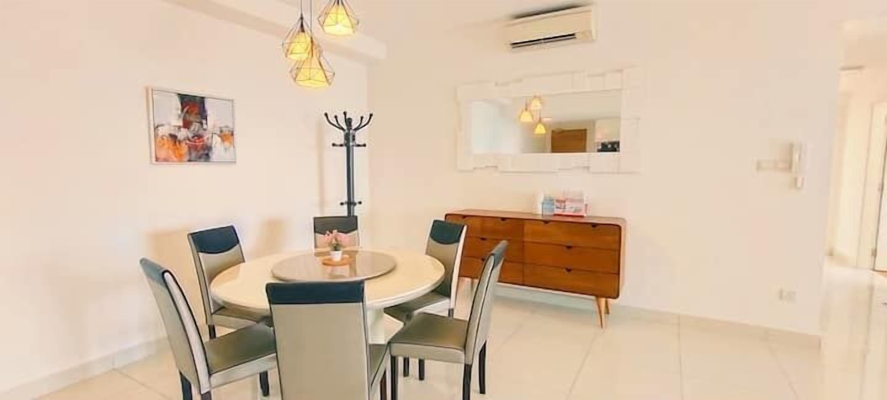 A dining area with a round table and chairs, a wooden dresser, and a coat rack.