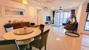 A modern living room with a dining area, a large window, and a hanging chair. - Teega Residence (Iskandar Puteri)