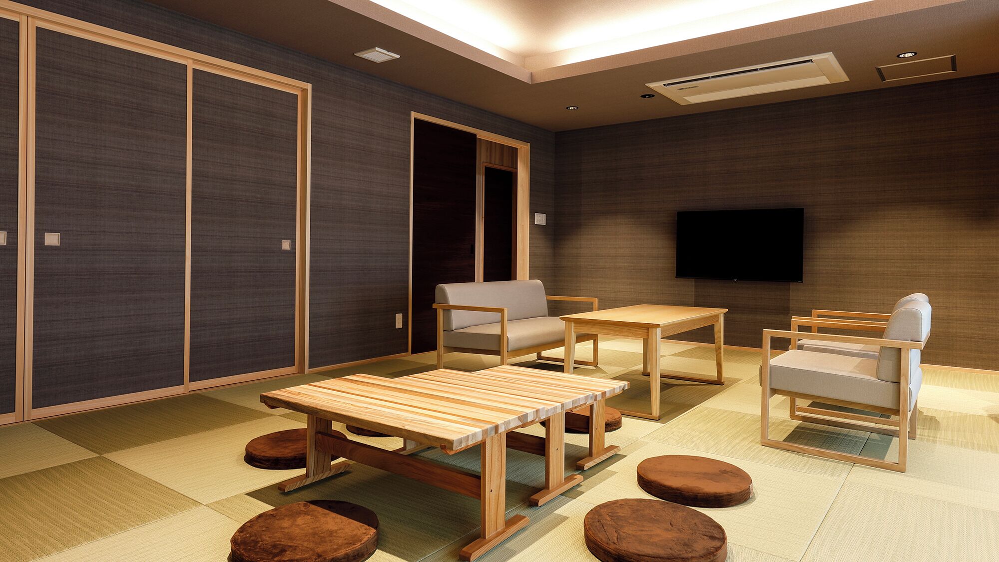 A modern room with a sofa, two chairs, a table, and a TV.