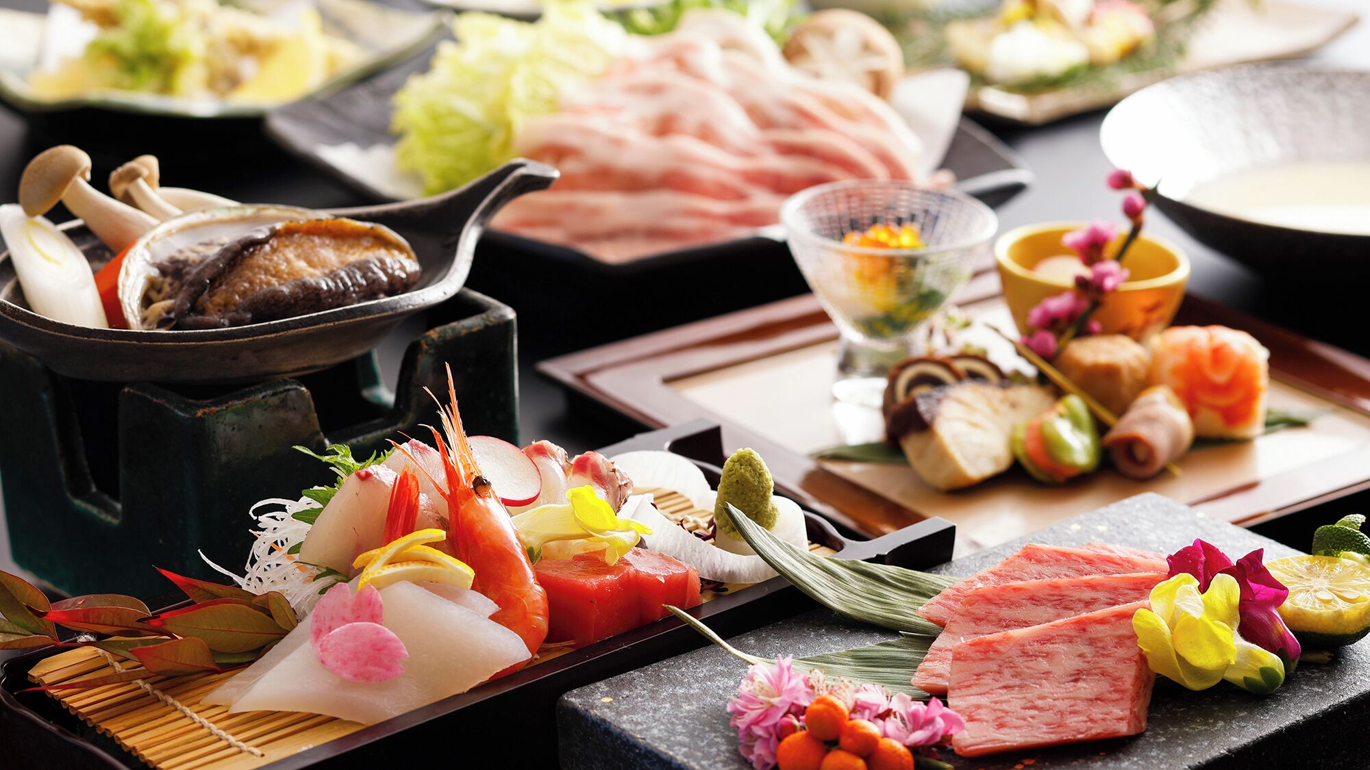 A variety of Japanese dishes including sashimi, sushi, and tempura, arranged on a table.