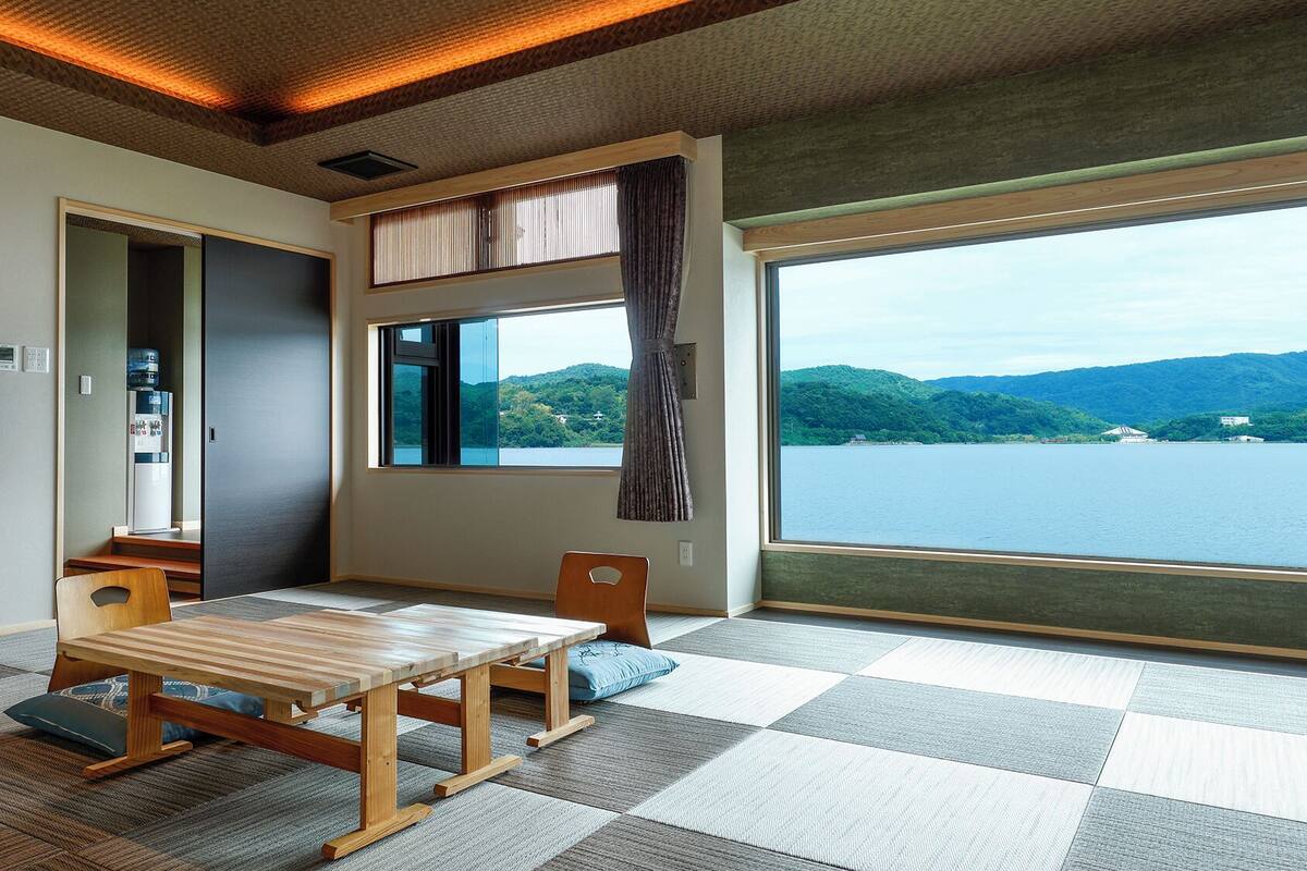 A room with a large window, a flat-screen TV, a water dispenser, and a wooden table.