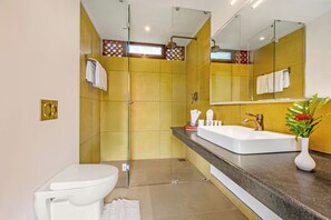 Un baño moderno con ducha de vidrio, lavamanos blanco y un espejo grande.