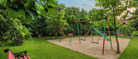 A playground with swings and a bench in a grassy area.