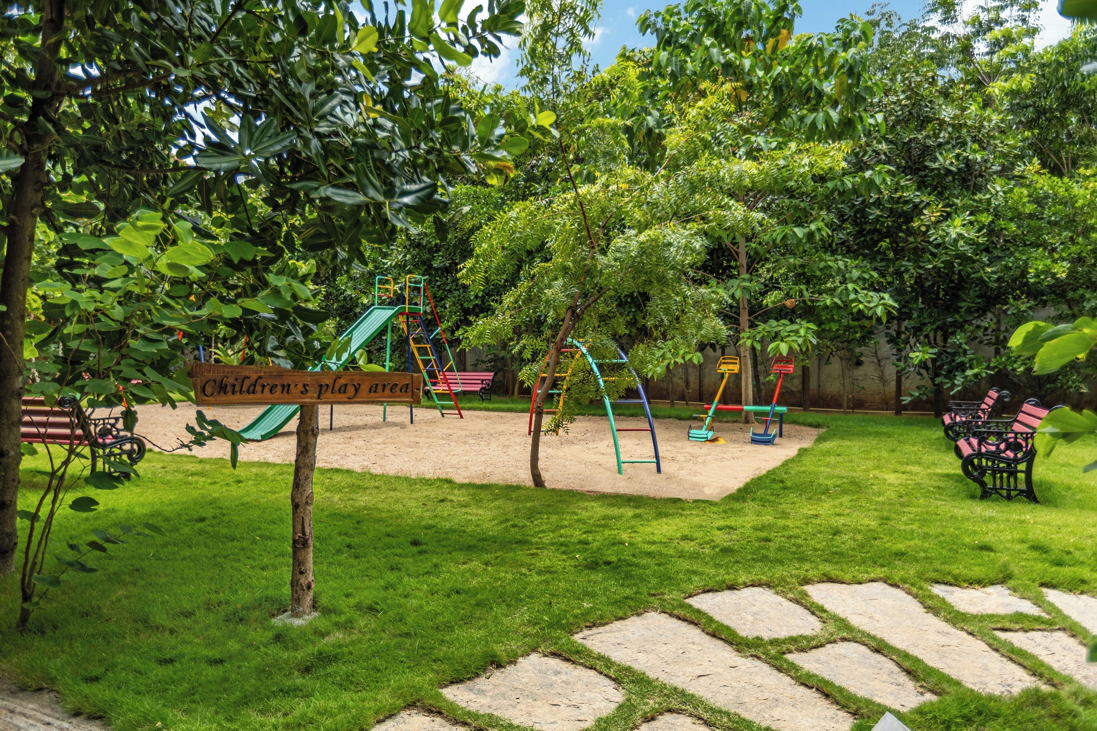 A children's play area with a sign, swings, and a bench.