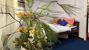 A bedroom with a bed, a nightstand, and a large floral arrangement.