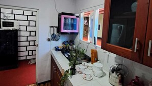 A compact kitchen with a microwave, a pink TV, and wooden cabinets.
