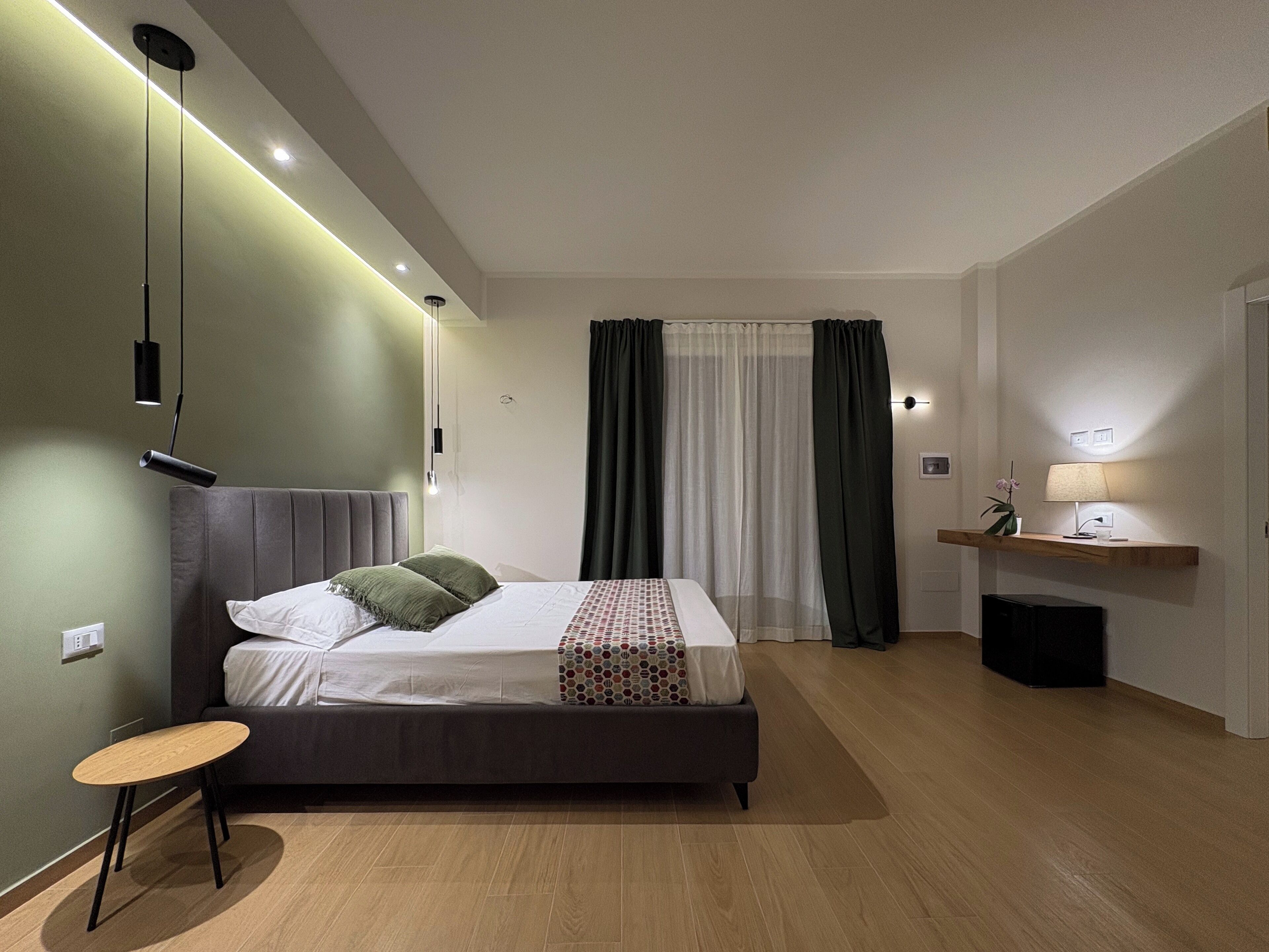 Un dormitorio moderno con una cama, una mesita de noche y un escritorio con lámpara.