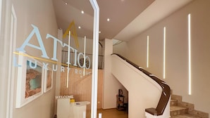 Un intérieur moderne avec un escalier, un comptoir d’accueil et une pancarte « Bienvenue ».